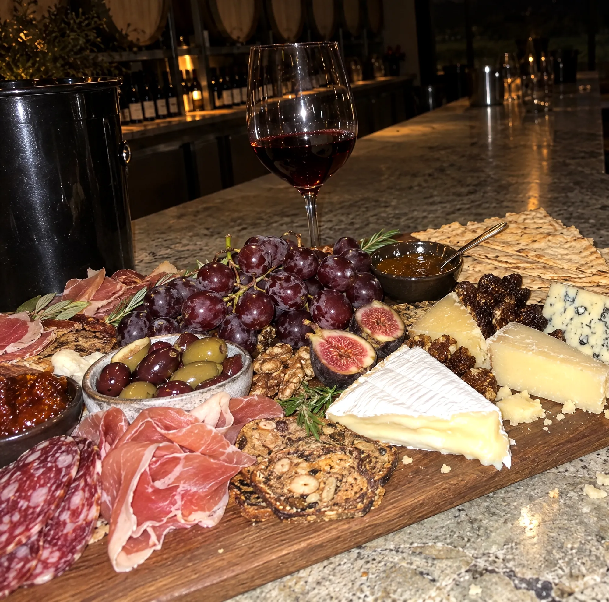 A grazing board of cured meats, cheeses and figs beside two glasses of red wine